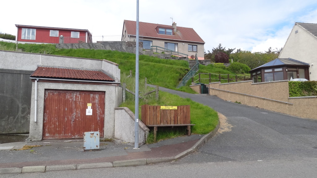 houses on a uphill street with a bench on the street corner